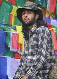 A good looking male tourist looking at camera while posing against buddhist prayer flags 