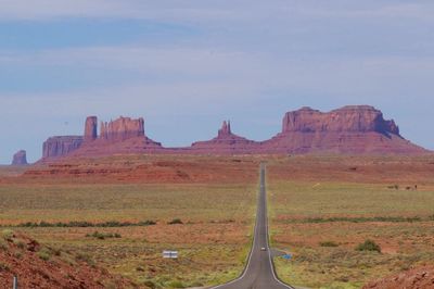 Panoramic view of road leading towards mountains against sky, monument valley