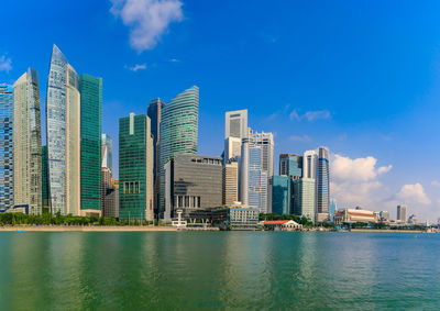 City at waterfront against blue sky