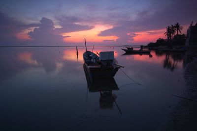 Boat in lake against sky during sunset