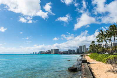 Scenic view of sea by city buildings against sky