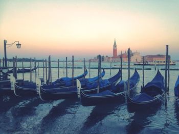 Boats moored in sea at sunset