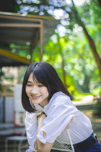 Portrait of smiling young woman against trees