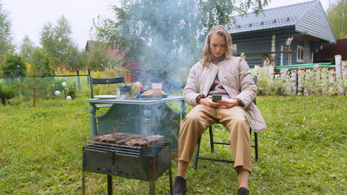 Woman using mobile phone while preparing food at yard