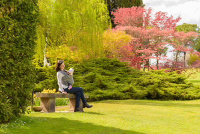 Woman sitting on bench in park during autumn