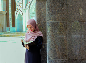 Full length of smiling woman standing against wall