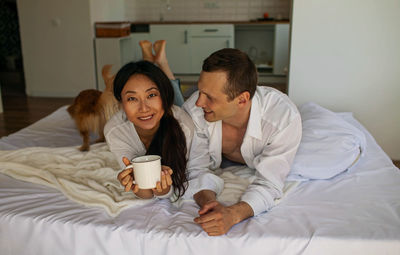 Couple with dog lying on bed at home