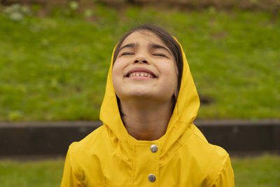 Child in nature under sun with a yellow rain coat