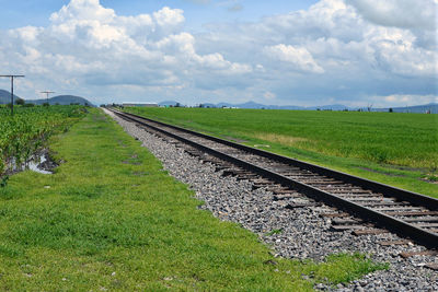 Railroad tracks on field against sky
