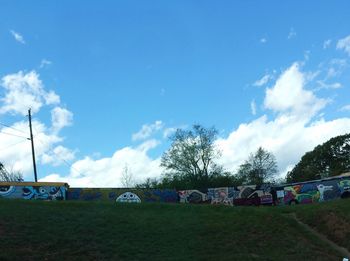 Trees on field against cloudy sky