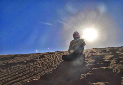 Man standing on sand against sky on sunny day