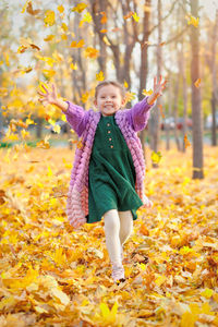 Portrait of young woman standing in forest during autumn