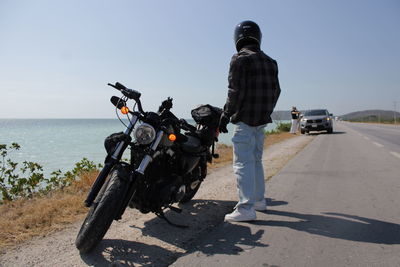Rear view of man riding motorcycle on road against sky