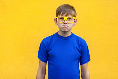 Portrait of boy standing against yellow background