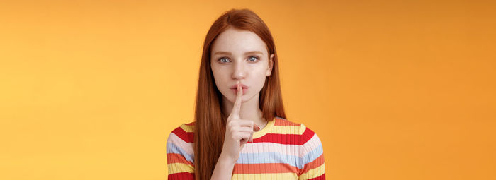 Portrait of young woman against yellow background