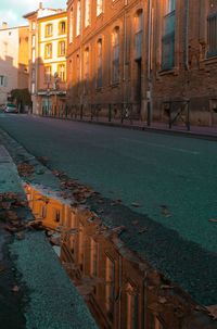 Street amidst buildings in city at sunset