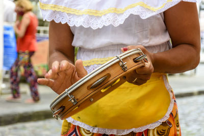 Woman in colorful ethnic clothes playing tambourine during a samba performance in salvador, bahia