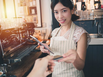 Portrait of a smiling young woman holding restaurant