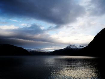 Scenic view of lake by mountains against sky