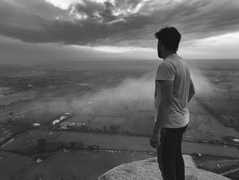 Rear view of man standing on landscape against sky