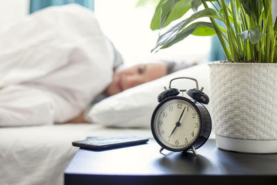 Close-up of alarm clock on bed at home