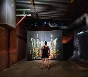 Full length rear view of woman standing against illuminated wall