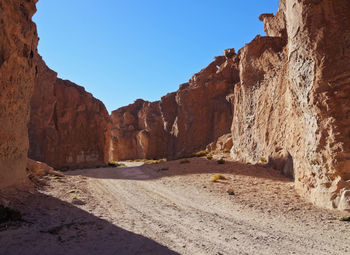 Road amidst rocks against clear blue sky