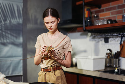 Side view of young woman standing against wall