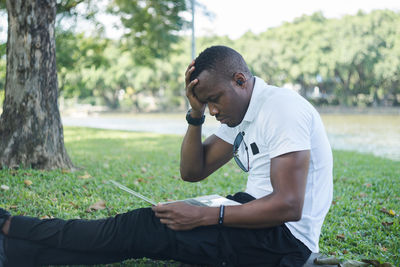 Young man looking away while sitting on land