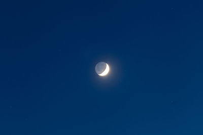 Low angle view of moon against blue sky