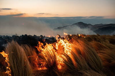 Panoramic view of bonfire on mountain against sky during sunset