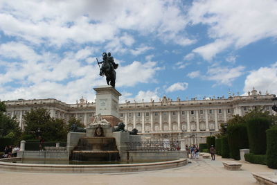 Statue in city against cloudy sky