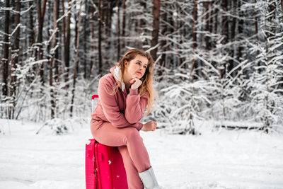 Woman sitting on snow covered land