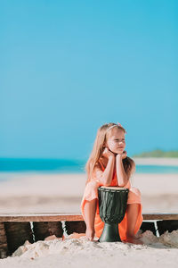 Full length of woman sitting on beach against sky