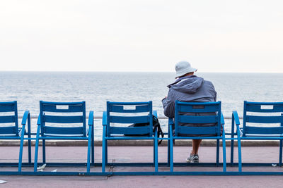 Rear view of man sitting on chair at beach