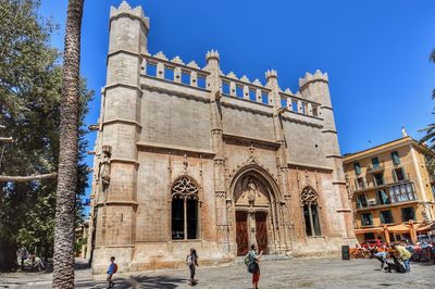 People in front of building against blue sky