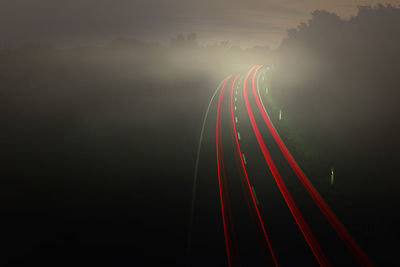 Light trails on bridge against sky at night