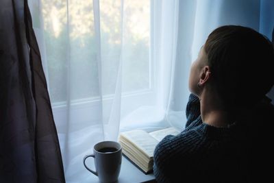 Close-up of woman sitting by coffee cup on table