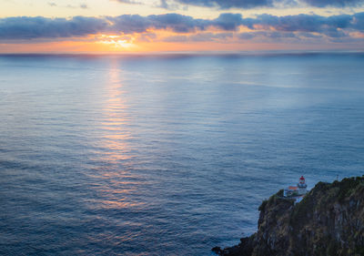 Scenic view of sea and lighthouse farol do arnel, azores, against sky during sunrise 