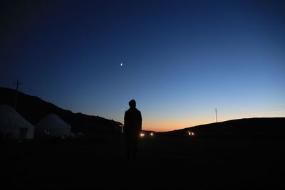 Silhouette man standing on shore against sky at night