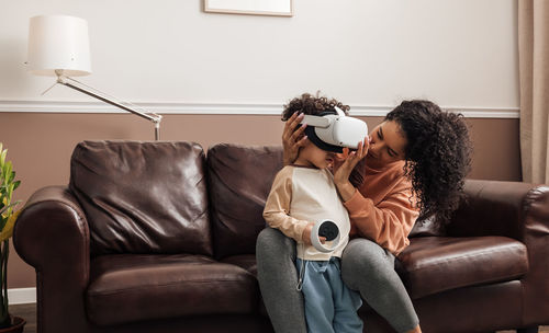 Mother helping son wearing virtual reality headset