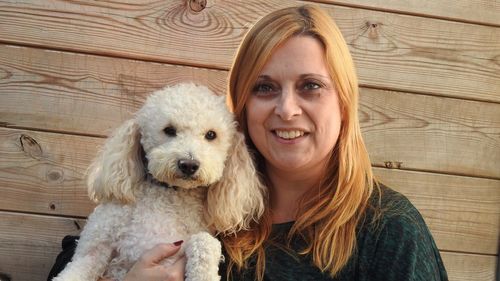 Portrait of woman with dog against wooden wall