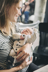 Smiling mother holding her sleeping baby in cafe