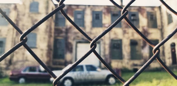 Close-up of chainlink fence against buildings in city