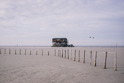 Pier on beach against sky