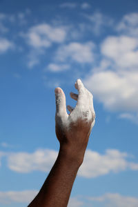 Low angle view of man hand against sky
