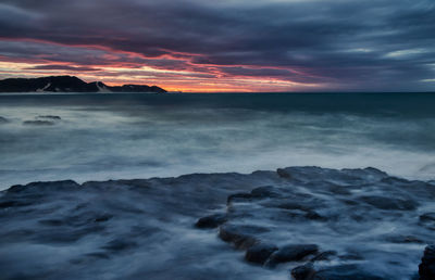 Scenic view of sea against dramatic sky during sunset