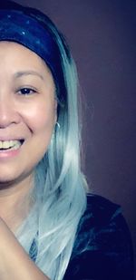 Close-up portrait of smiling young woman against gray background