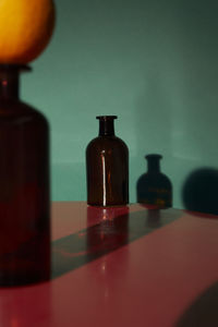 Close-up of glass bottle on table against wall