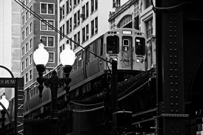 Low angle view of train on bridge against buildings in city